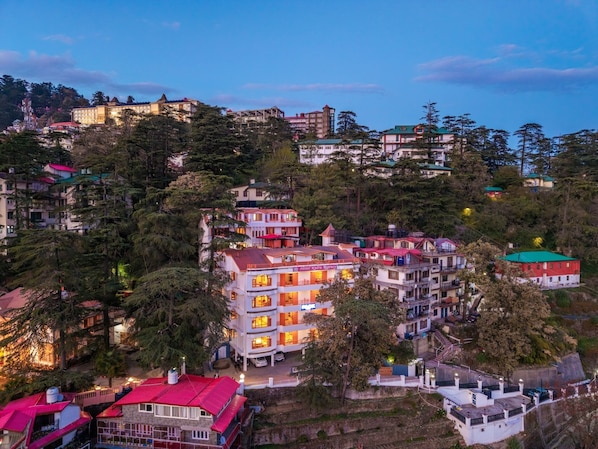 A multi-story hotel with balconies, surrounded by trees and other buildings.