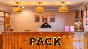 A reception desk with a 'PACK' sign, a man standing behind it, and three hanging lamps. - PACK Shimla (Shimla)