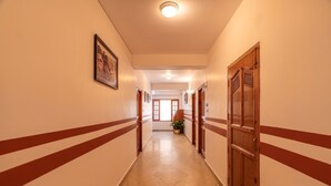 A hallway with a marble floor, wooden doors, and a framed picture on the wall. - PACK Shimla (Shimla)