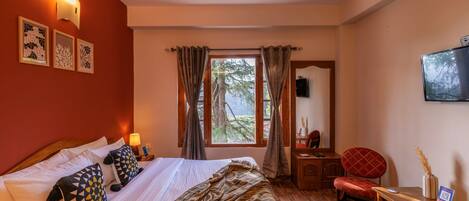 A hotel room with a bed, a desk, a chair, a window with curtains, and wall-mounted artwork.