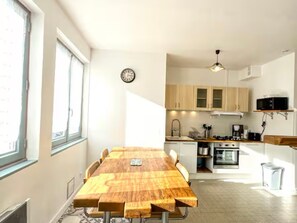 A compact kitchen with a dining table, a clock, and a microwave. - Central house, pets welcome - 4 guests (La Roche-Posay)