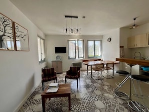 A modern kitchen with a dining area, a TV mounted on the wall, and patterned floor tiles. - Central house, pets welcome - 4 guests (La Roche-Posay)