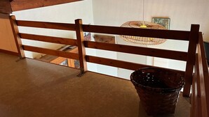 A wooden balcony with a view of a room, a wicker basket, and a hanging light fixture. - Mezzanine apartment near ocean - 4 guests (Capbreton)