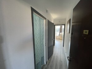 Ein Flur mit einer Tür mit Muster, einem Bett mit gestreifter Bettdecke und einer Tür mit der Nummer 58.