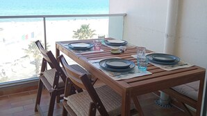 A wooden table with plates and glasses, set against a balcony with a view of the beach and ocean. - Studio cabin, AC, sea view - 5 guests (Canet-Plage)