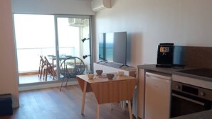 A modern kitchen with a dining area, a TV, and a coffee machine. - Studio cabin, AC, sea view - 5 guests (Canet-Plage)