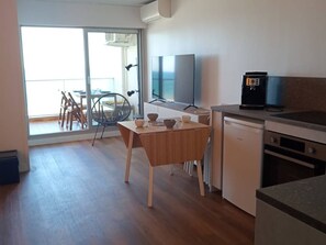 A modern kitchen with a dining area, a TV, and a coffee machine. - Studio cabin, AC, sea view - 5 guests (Canet-Plage)