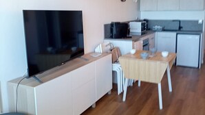 A compact living space with a flat-screen TV, a kitchenette, a dining area with a table and chairs, and a small kitchen with appliances. - Studio cabin, AC, sea view - 5 guests (Canet-Plage)