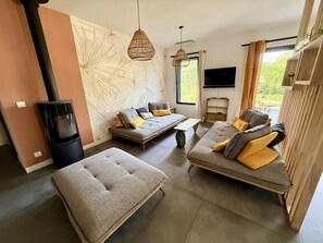 Ein modernes Wohnzimmer mit einer Sofagarnitur, einem Hocker und einem Kamin.