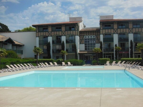 Ein Hotel mit Schwimmbad, Liegestühlen und traditioneller Architektur.