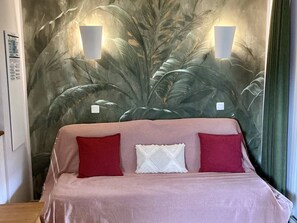 Ein Bett mit einer rosa Decke, zwei roten Kissen und einem weißen Kissen.