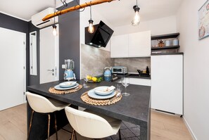 Een moderne keuken met een centraal eiland, witte barkrukken, een ingebouwde oven en een magnetron.