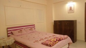 Ein Schlafzimmer mit Bett, Nachttisch, Kleiderschrank und einem gerahmten Bild an der Wand.