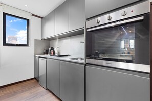 Eine moderne Küche mit Edelstahlgeräten, einem eingebauten Backofen und einem Fenster mit Blick auf die Stadt.