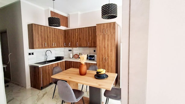 Una cocina moderna con armarios de madera, piso de mármol y una mesa de comedor con sillas.