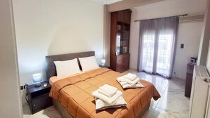 Habitación de hotel con una cama grande, una mesita de noche, un armario y baño con cortina de ducha.