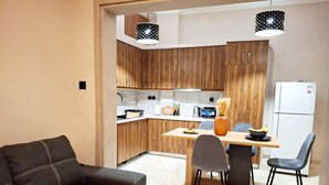 Una cocina moderna con armarios de madera, una mesa de comedor con sillas y un sofá negro.