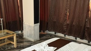 Una habitación de hotel con una cama, una mesita de vidrio y cortinas.