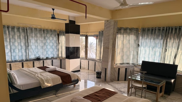 Una habitación de hotel con dos camas, televisión, escritorio y ventilador de techo.