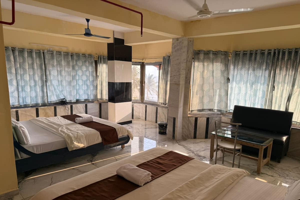 Una habitación de hotel con dos camas, televisión, escritorio y ventilador de techo.