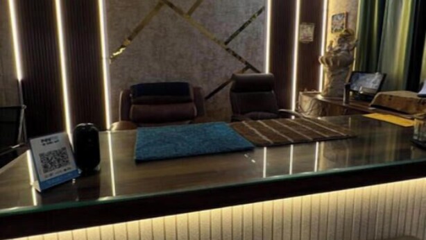 A reception desk with a blue mat, a clock on the wall, and a statue. - Hotel Star (Shivpuri)