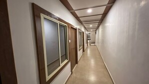 A long, narrow hallway with wooden doors and a tiled floor. - Hotel Star (Shivpuri)