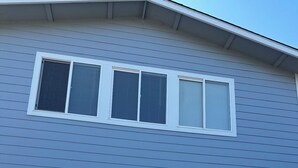 A house with a garage door, a window with shutters, and a side view of a car parked in front.