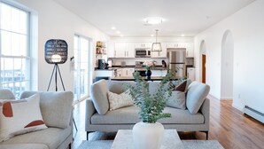 A modern living room with a sofa, a coffee table, and a vase of flowers. - Spacious Summer Oaisis 4-bedroom house with AC in Kerhonkson (Kerhonkson)