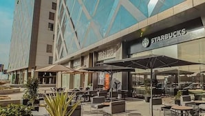 Una Starbucks con mesas al aire libre y fachada de edificio moderna.