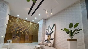 Un vestíbulo moderno con una recepción, una zona de estar con sofá y mesa de centro, un cuadro abstracto de gran tamaño y una planta en maceta.