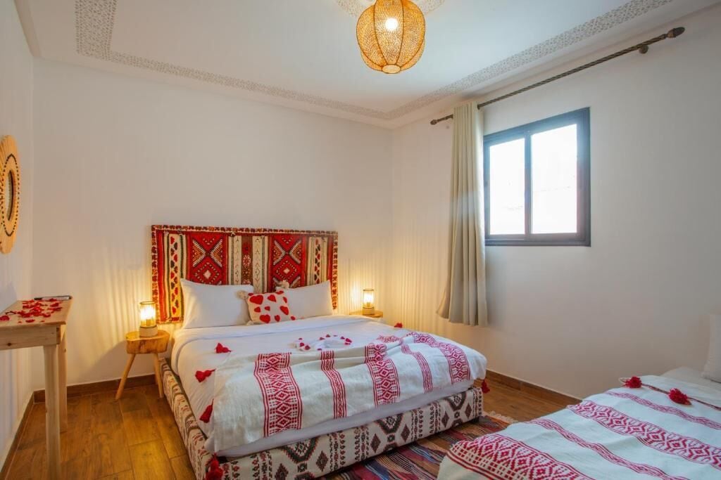 A hotel room with a bed, bedside tables, a window, and a decorative ceiling light.