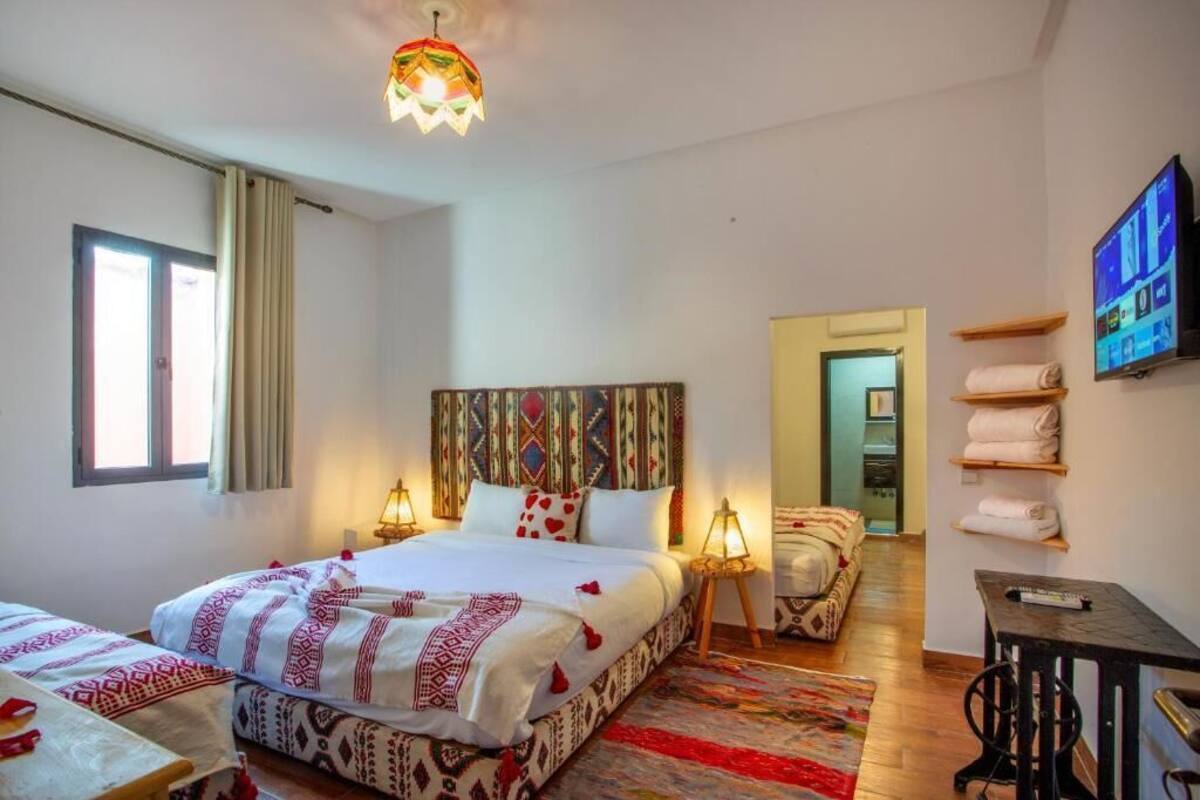 A hotel room with a bed, bedside tables, a TV, a desk, and a chair.