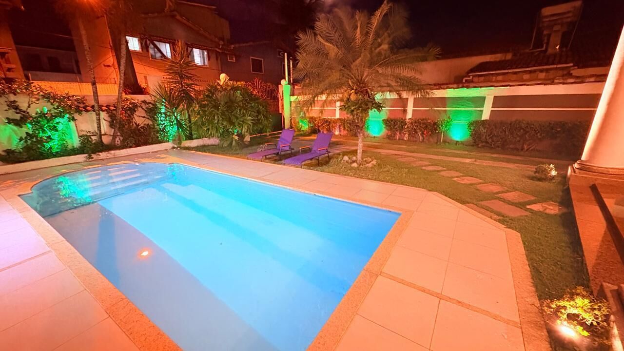 A swimming pool with lounge chairs, surrounded by well-maintained landscaping and illuminated by ambient lighting.