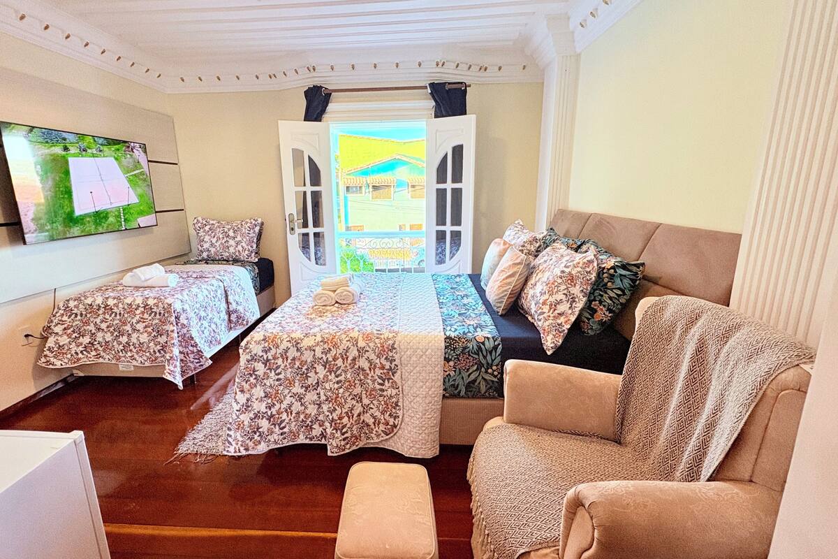 Une chambre avec deux lits, un canapé, une télévision et une fenêtre avec des rideaux.