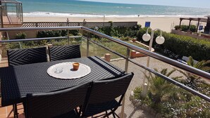 A balcony with a table and chairs overlooking a beach. - Gava Mar Apartment With Beach View (Gava)