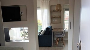 A bedroom with a bed, a TV mounted on the wall, a window, and a view of the outside. - Gava Mar Apartment With Beach View (Gava)