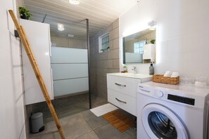 Une salle de bain moderne équipée d’un lave-linge, d’un miroir et d’une échelle en bois appuyée contre le mur.