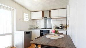 Una cocina con armarios blancos, una campana extractora de acero inoxidable y una mesa de comedor con sillas.