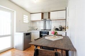 A kitchen with white cabinets, a stainless steel range hood, and a dining table with chairs.