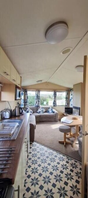 Interni di un camper compatto con angolo cottura, zona salotto e finestra vista esterna.