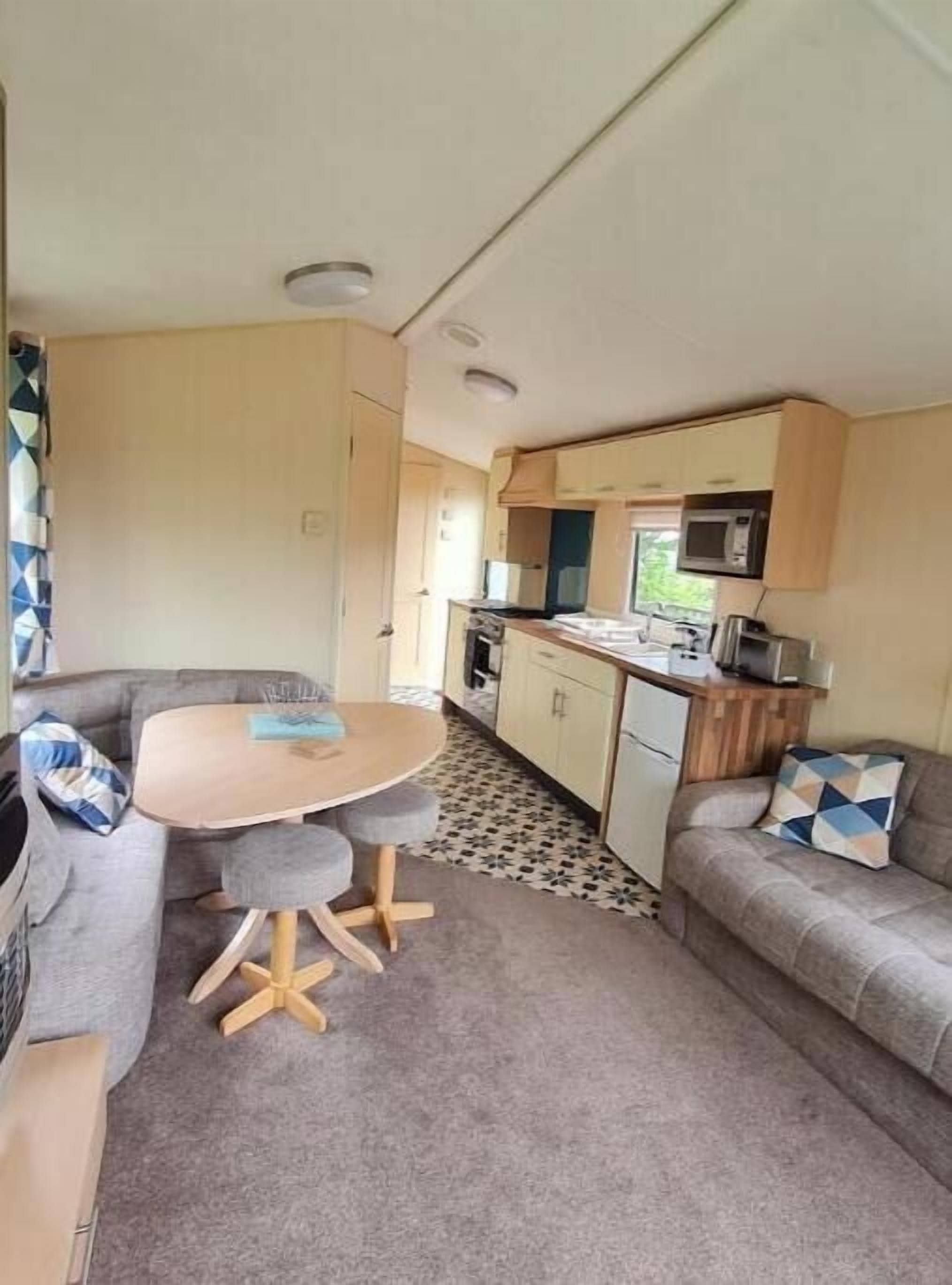 A compact RV interior with a dining area, kitchenette, and seating space.