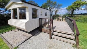A mobile home with a deck, a window, and a small outdoor area.