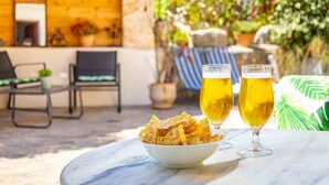 Una mesa con un bol de papas fritas y dos vasos de cerveza, con asientos al aire libre y una pared de madera.