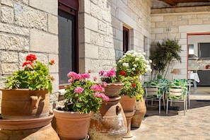 A courtyard with terracotta planters, outdoor seating, and a stone building.