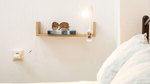 Una mesita de noche con un par de gafas, un libro y una lámpara.