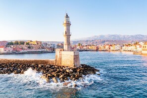 Une ville côtière qui se distingue par son phare imposant, son brise-lames rocheux et les bâtiments qui bordent le front de mer.