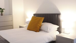 Un dormitorio moderno con cama, mesitas de noche y una viga en el techo.