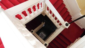 Una escalera con peldaños alfombrados de rojo y barandillas blancas.
