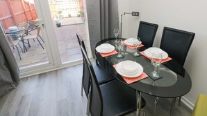 A dining area with a glass table, black chairs, and a view of a backyard through a sliding door. - The Gower Gateway (Swansea)