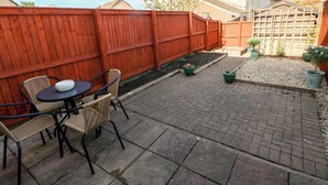A patio with a table and chairs, a red fence, and potted plants. - The Gower Gateway (Swansea)